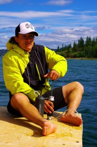 Brian filtre de l'eau pour l'équipe. Sur le Yukon, il suffit de plonger l'embout du filtre dans l'eau du fleuve et de pomper pour obtenir de l'eau fraîche et potable. Pas tout à fait claire par endroits, le filtre s'encrasse vite et nous devons le nettoyer chaque jour.
