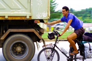 Etienne en pleine action dans notre nouveau moyen de transport : le vélo tracté par un camion. Ça fatigue moins et ça va plus vite ! En général les conducteurs de camion ralentissent un peu pour nous donner un coup de main sur plusieurs dizaines de kilomètres.